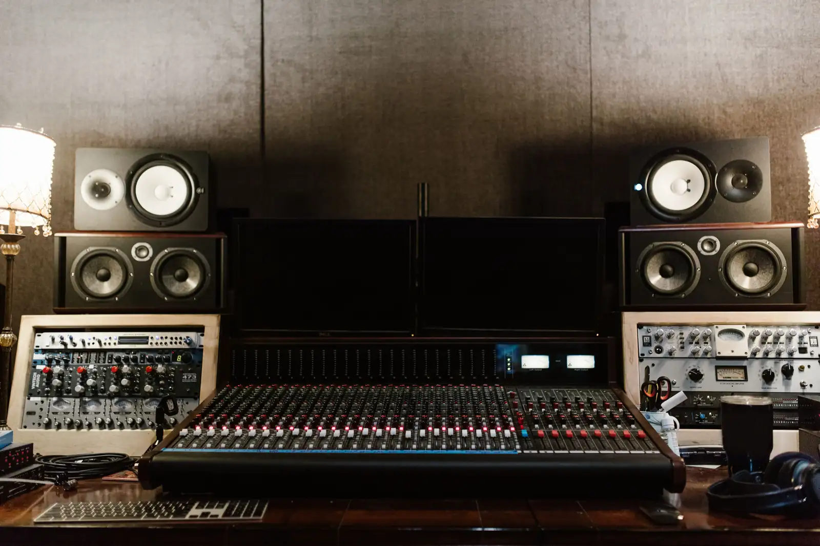 Stacked studio monitors on both sides of a mixing console in a recording studio