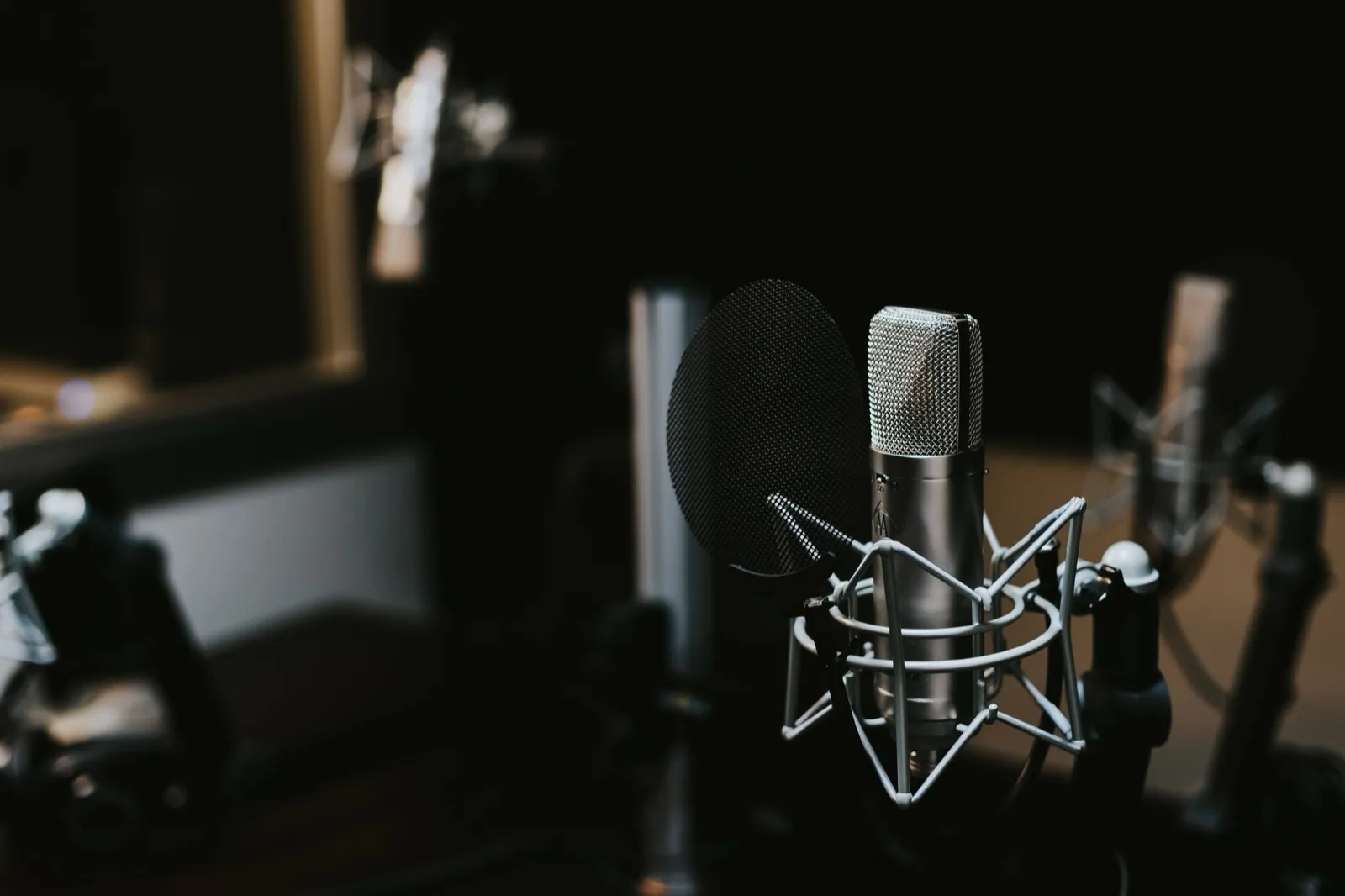 Condenser microphone in a shock mount with a pop filter in a dark studio