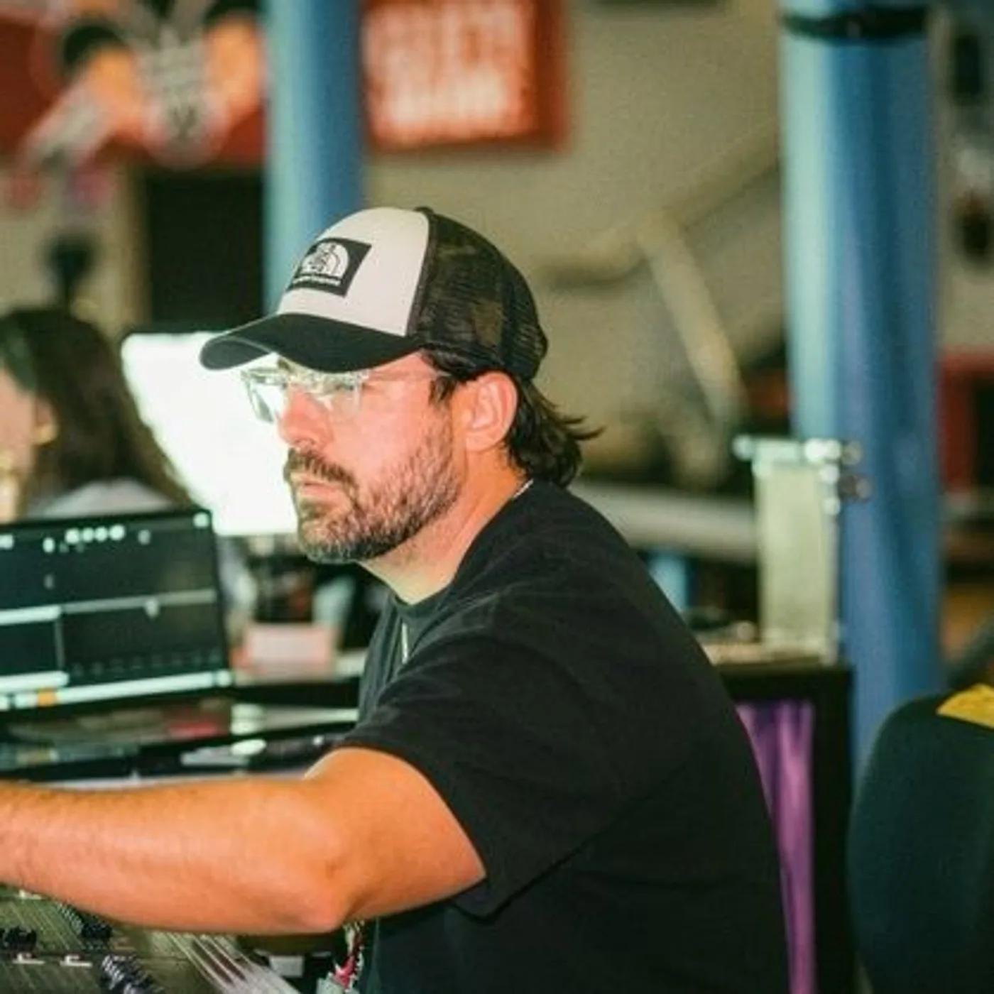 Ashton Parsons in a cap and glasses working at a live mixing console