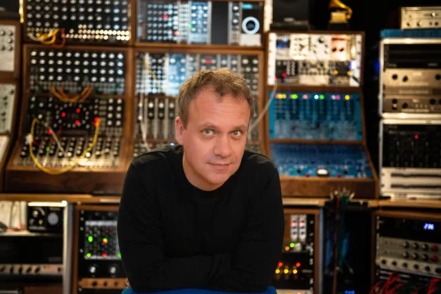 Dom Morley in a studio in front of racks of modular synthesisers
